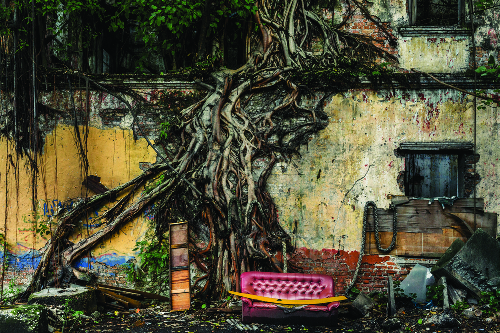 A Sofa Outside an Abandoned Shop Lot. Port Klang, Selangor, Malaysia. Jalan Kem used to be a busy main street 15 years ago. While the terminals of Port Klang today have grown to become the country's largest port and the twelfth busiest container port in the world, the town itself is full of abandoned, burnt-out and dilapidated pre-war buildings. The flyover connecting Northport and Westport is only a few metres from the shop lots and as a consequence has devalued these colonial buildings and sucked the life from the area. Standing on the second floor of one of these buildings will give you a very close-up view of the concrete visual blight above. Coffee shop operator Yap Yong Choon, 56, said many shops had closed down after the elevated highway opened more than 10 years ago. He said the highway had taken away the glitter from the popular Jalan Kem. ìIt was the busiest street then. Now you can see for yourself the unoccupied and abandoned premisesíí.